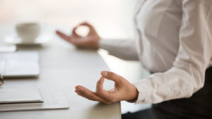 View of business person's torso and arms, seated at a desk, practicing mindfulness techniques for entrepreneurs